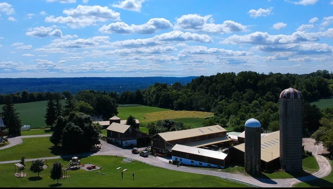 Aerial view of the farmstead's barns and two silos, with fields and the Dundas Valley stretching beyond
