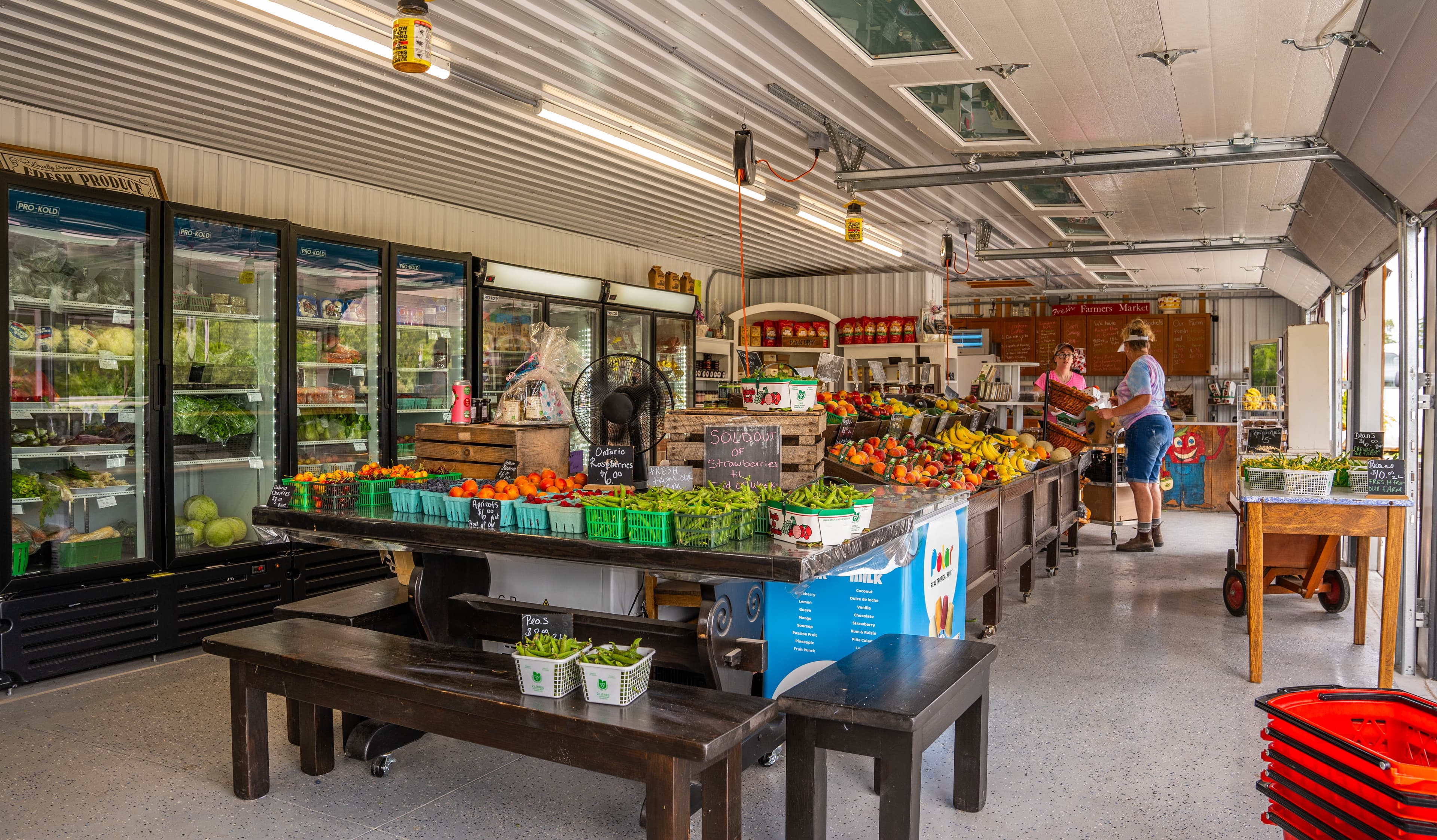 Tables of green beans, peaches, tomatoes and bananas in the Moore Farms store, with coolers of greens along the wall