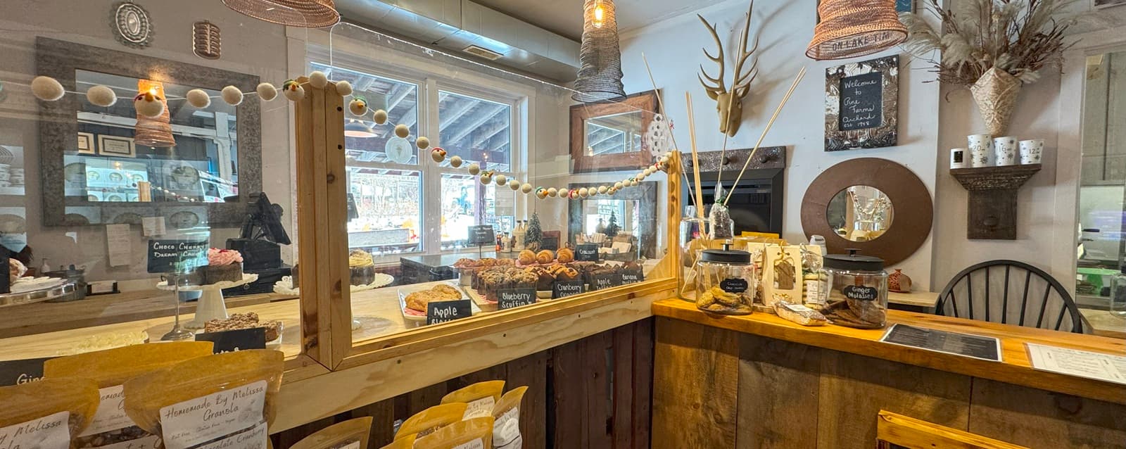 The bakeshop counter, with trays of muffins, scones and apple pastries behind a glass screen and a Welcome to Pine Farms Orchard sign on the wall