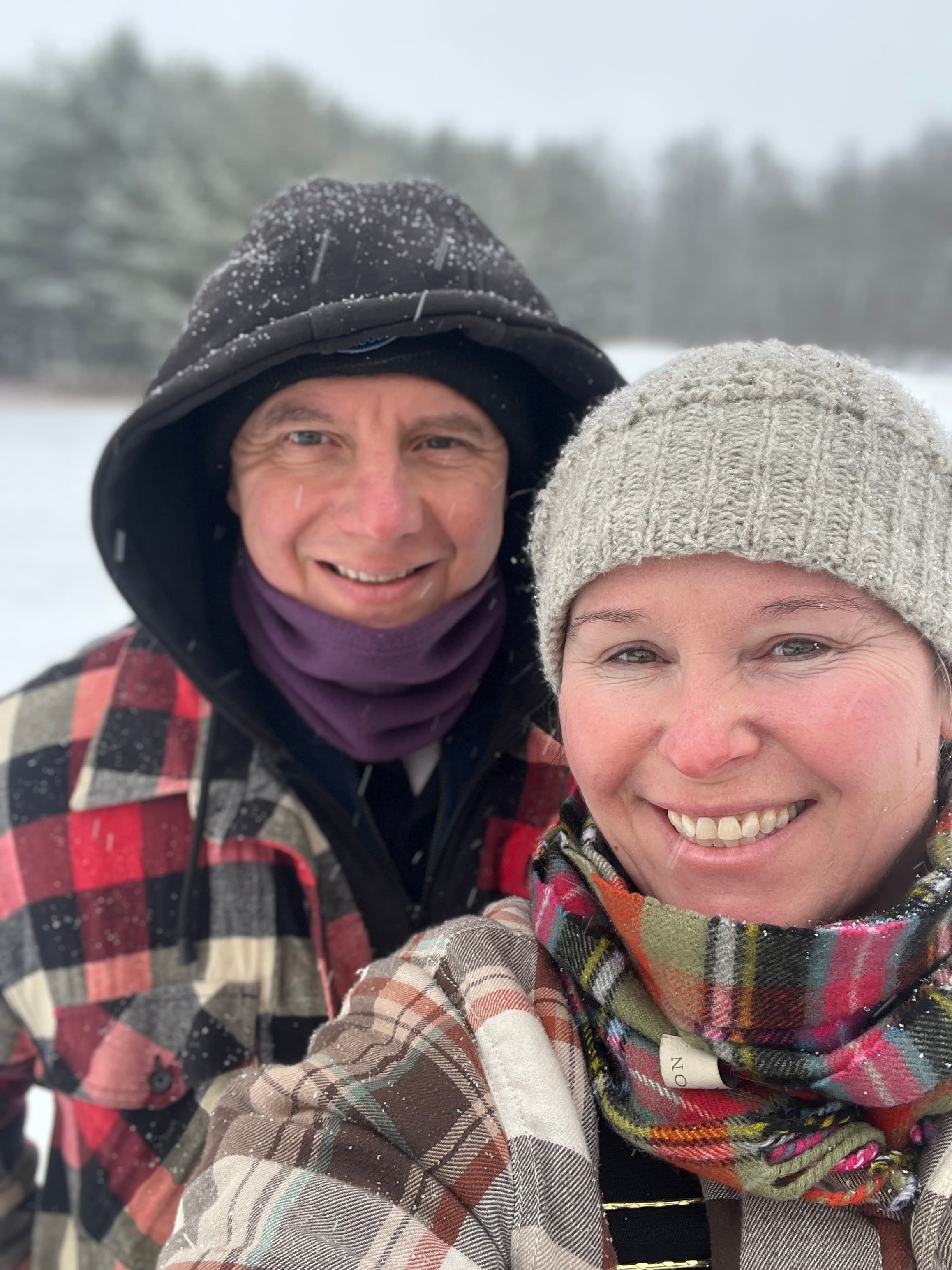 John and Christine Veit smiling in a snowy field in winter coats and hats